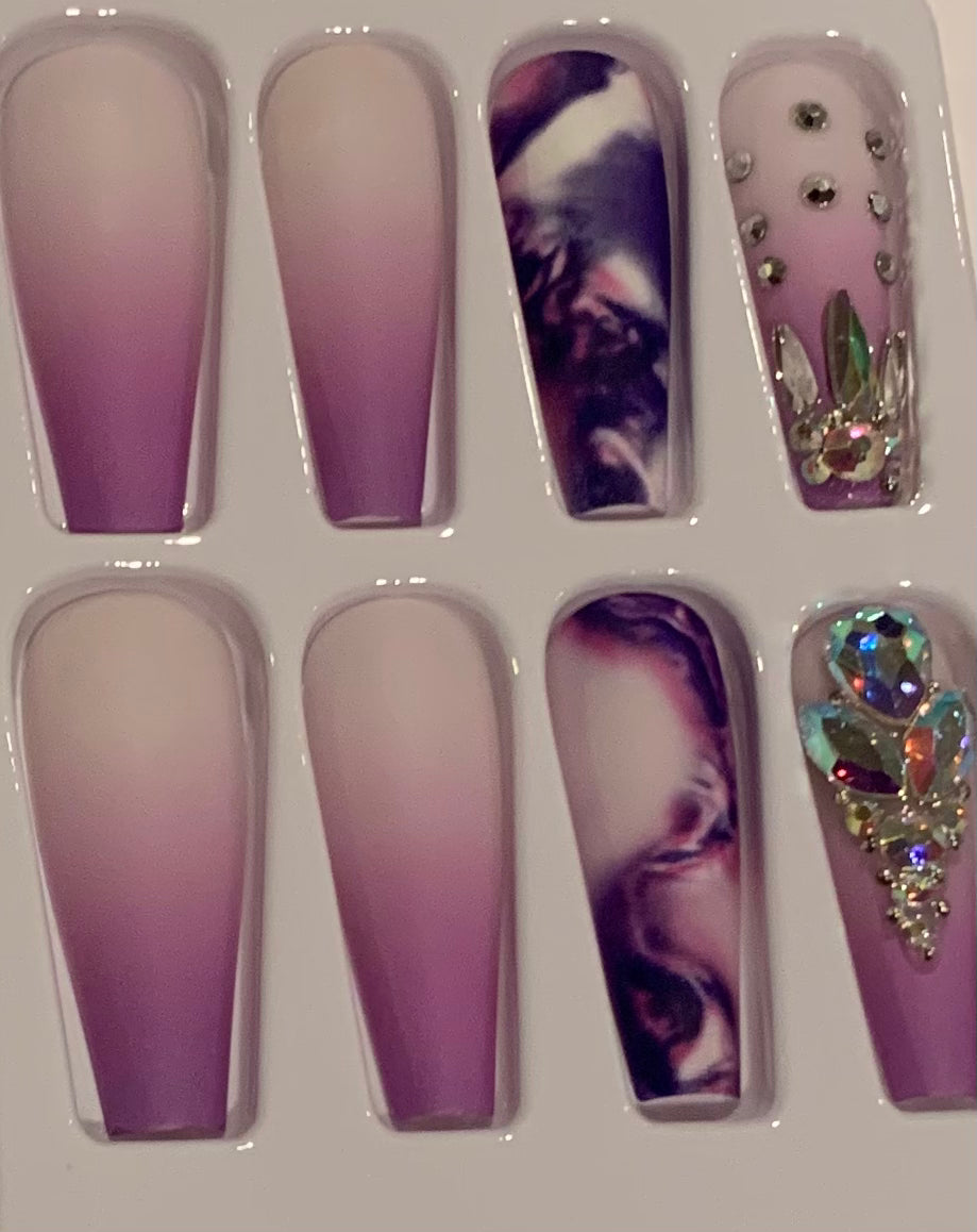 Set of purple nail art designs with marbled patterns and rhinestones.