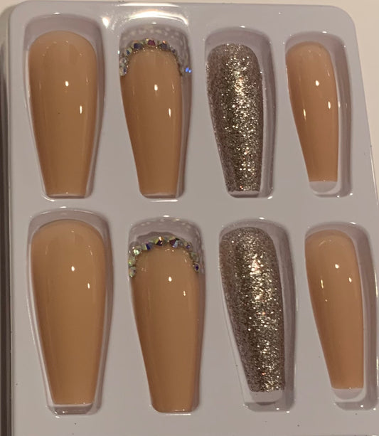 Set of false nails with beige, glittery gold, and rhinestone designs.  