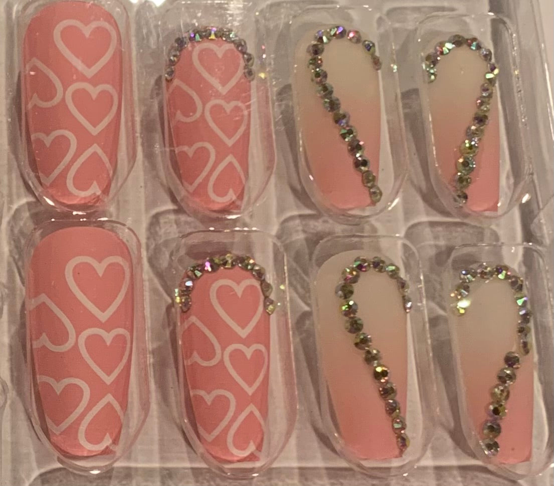Set of false nails with pink design and rhinestone embellishments. 